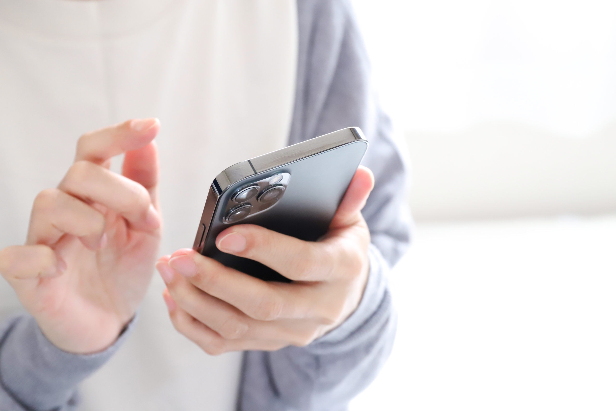 スマートフォンを片手で持ち、もう片方の手の指で画面を操作している手元の様子